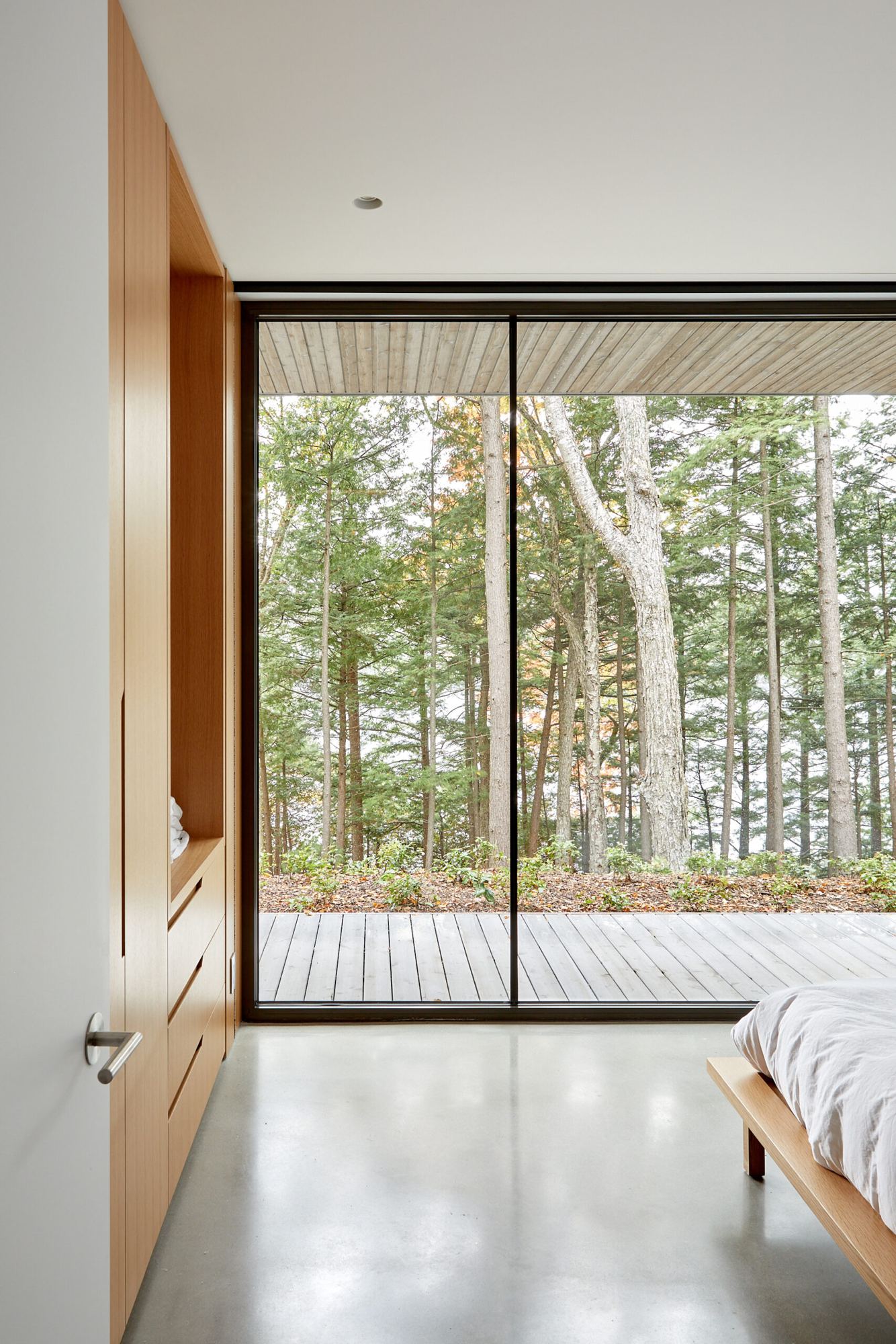 Bedroom opening onto the autumn forest through a large window