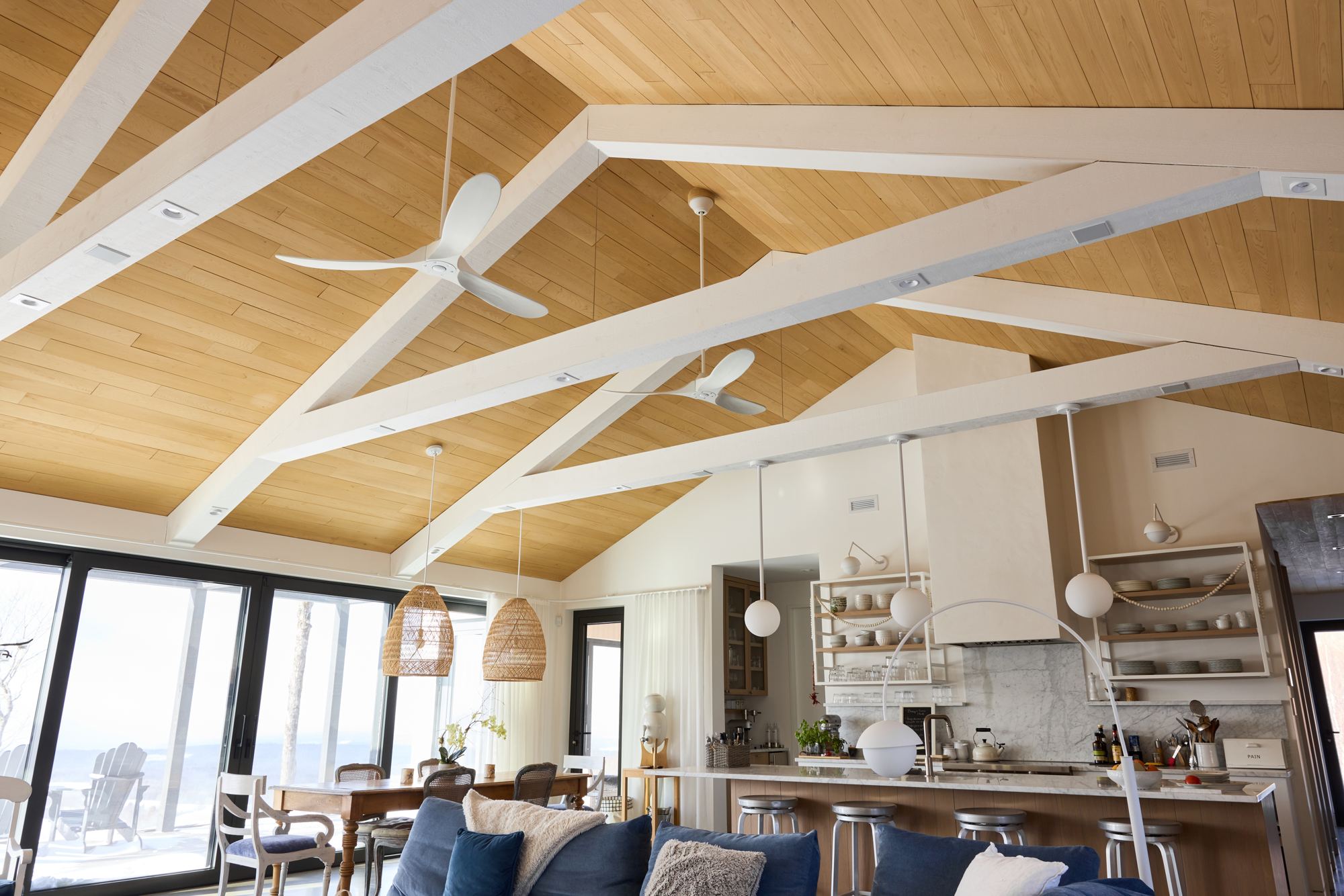 Large open room with a wood cathedral ceiling, kitchen and living area full of light