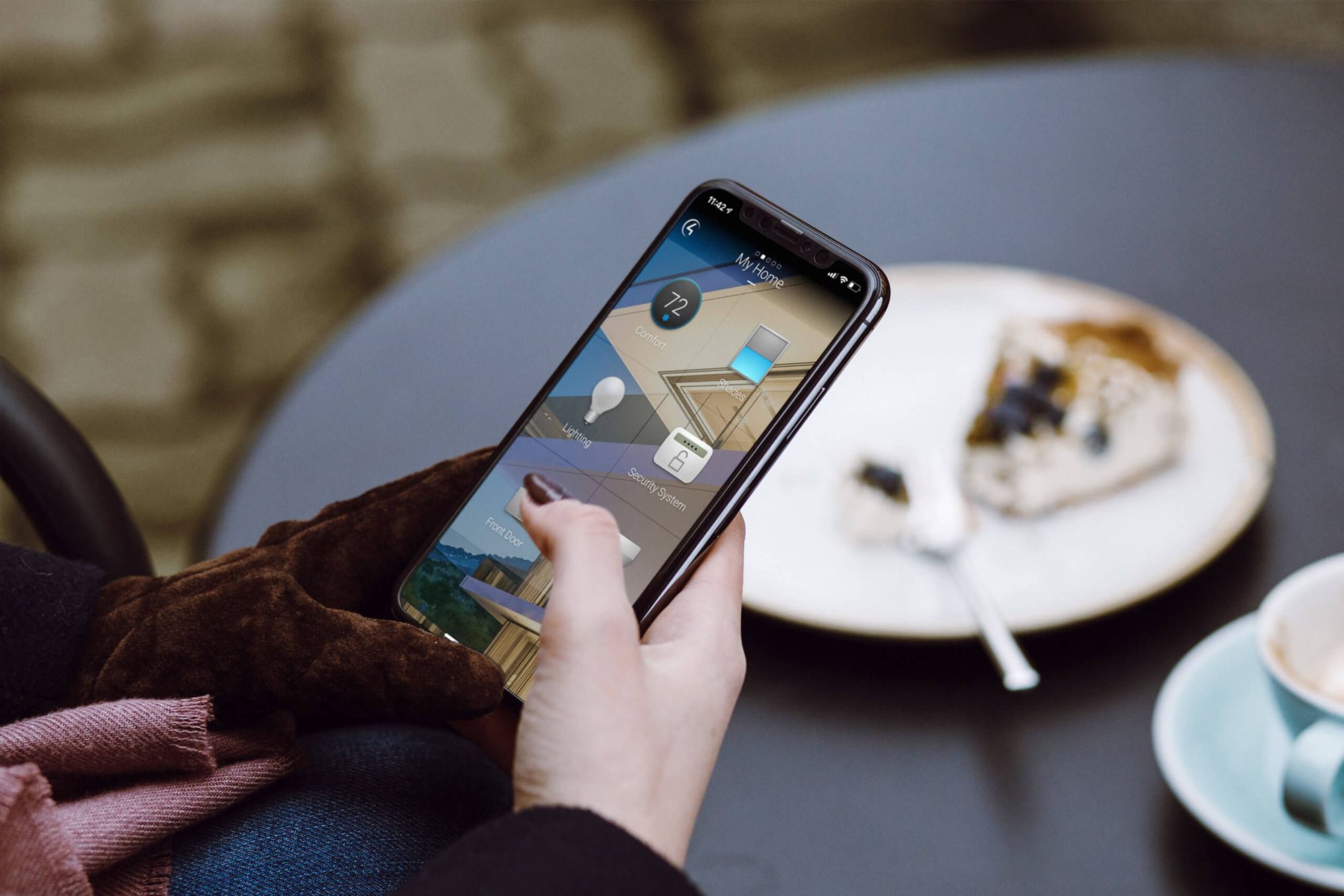 Personne qui contrôle sa maison sur son téléphone à côté d'un café et d'un dessert
