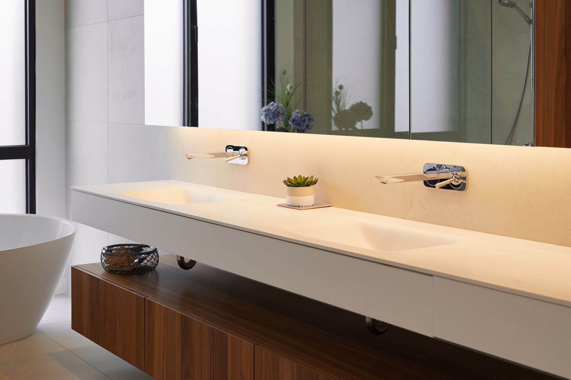Salle de bain épurée avec un éclairage doux sous le comptoir et derrière le miroir