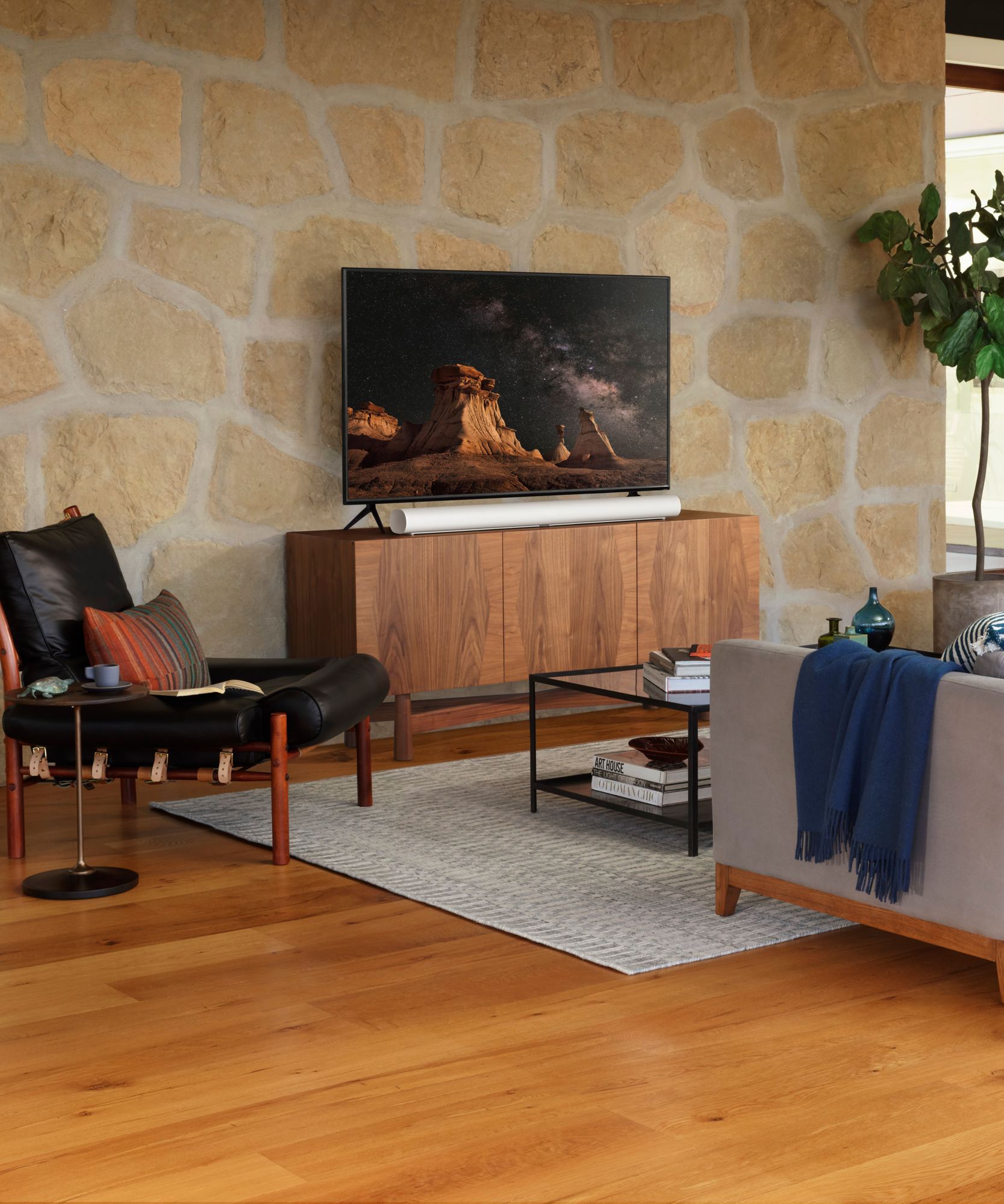 Salon chaleureux avec téléviseur au-dessus d'un meuble en bois et mur de pierre