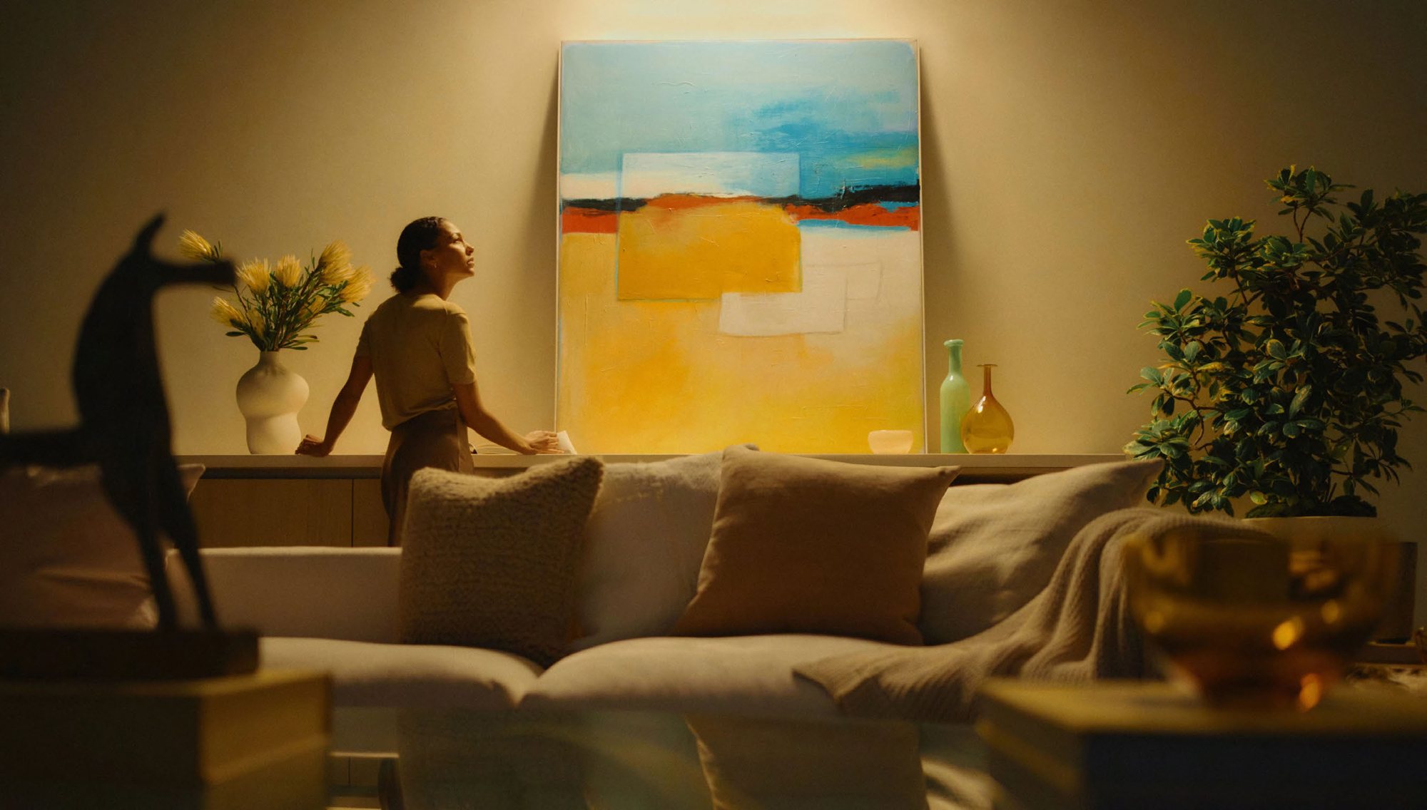 Femme assise devant un grand tableau coloré éclairé par Ketra
