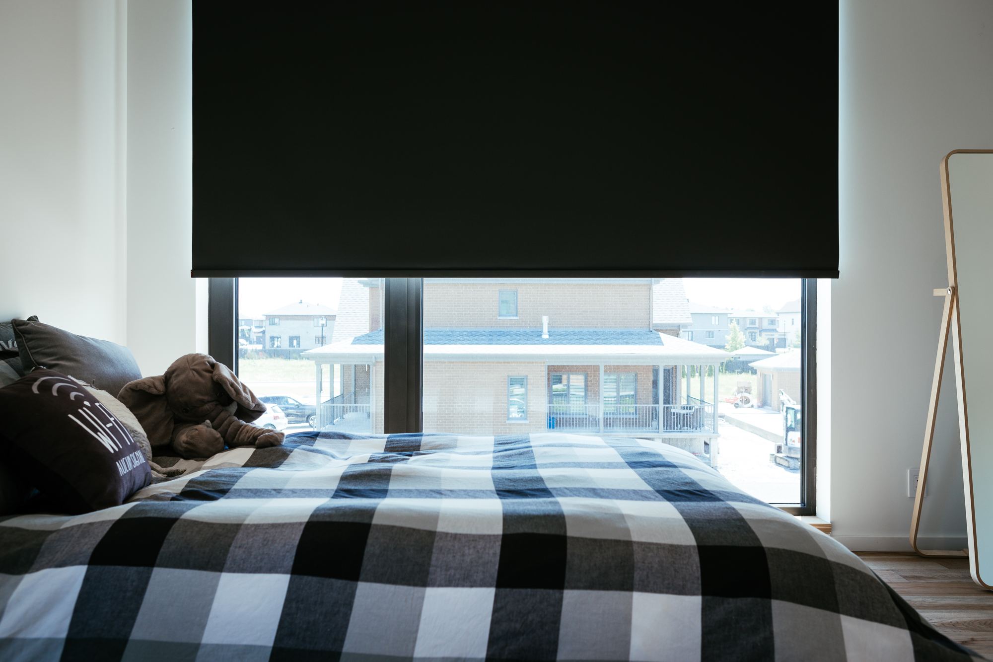 Chambre avec toile opaque baissée devant une grande fenêtre